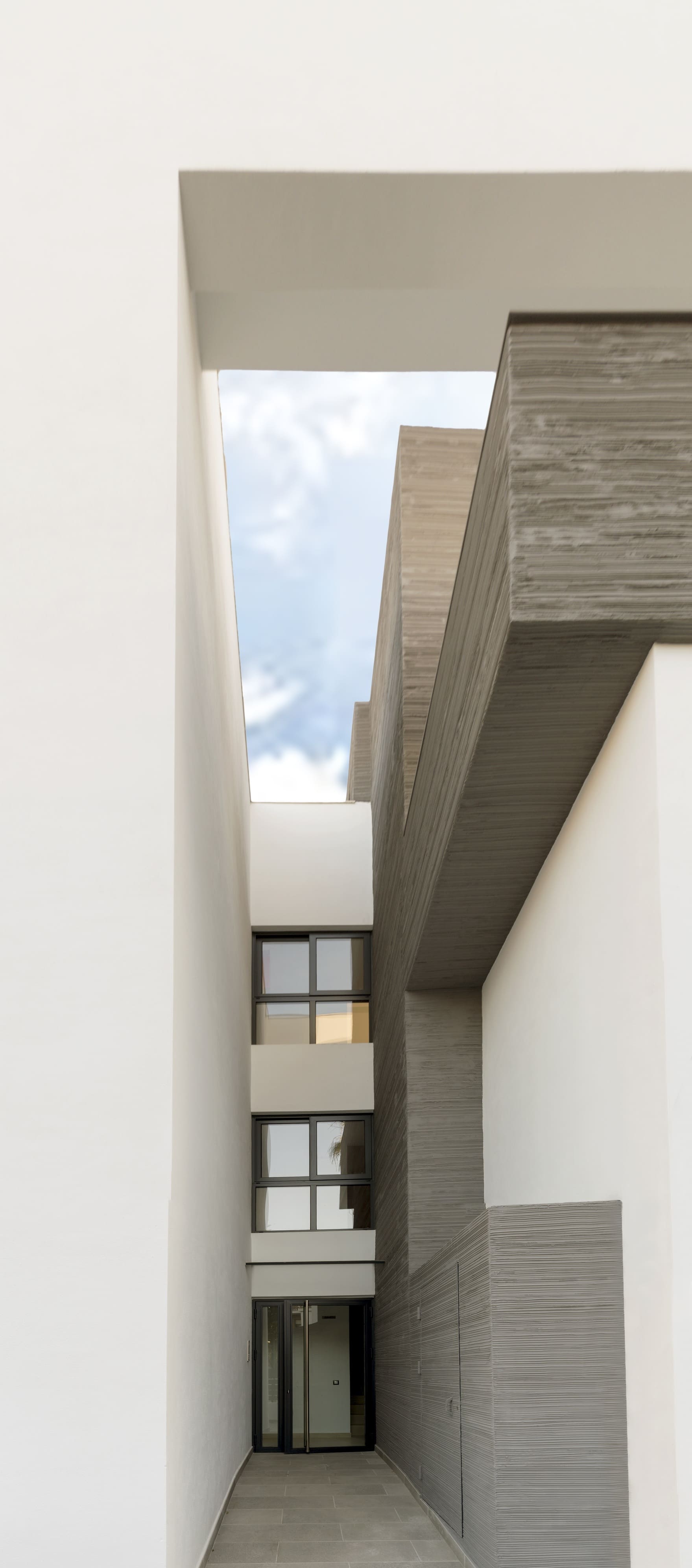 Patio interior vertical en la Casa Ocaña con pasillo de acceso y luz cenital