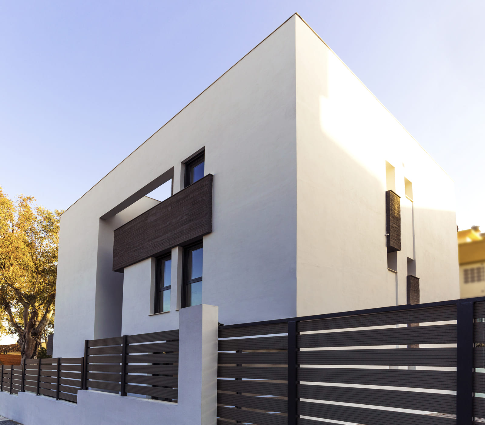 Fachada lateral de la Casa Ocaña con valla metálica y ventanas cuadradas