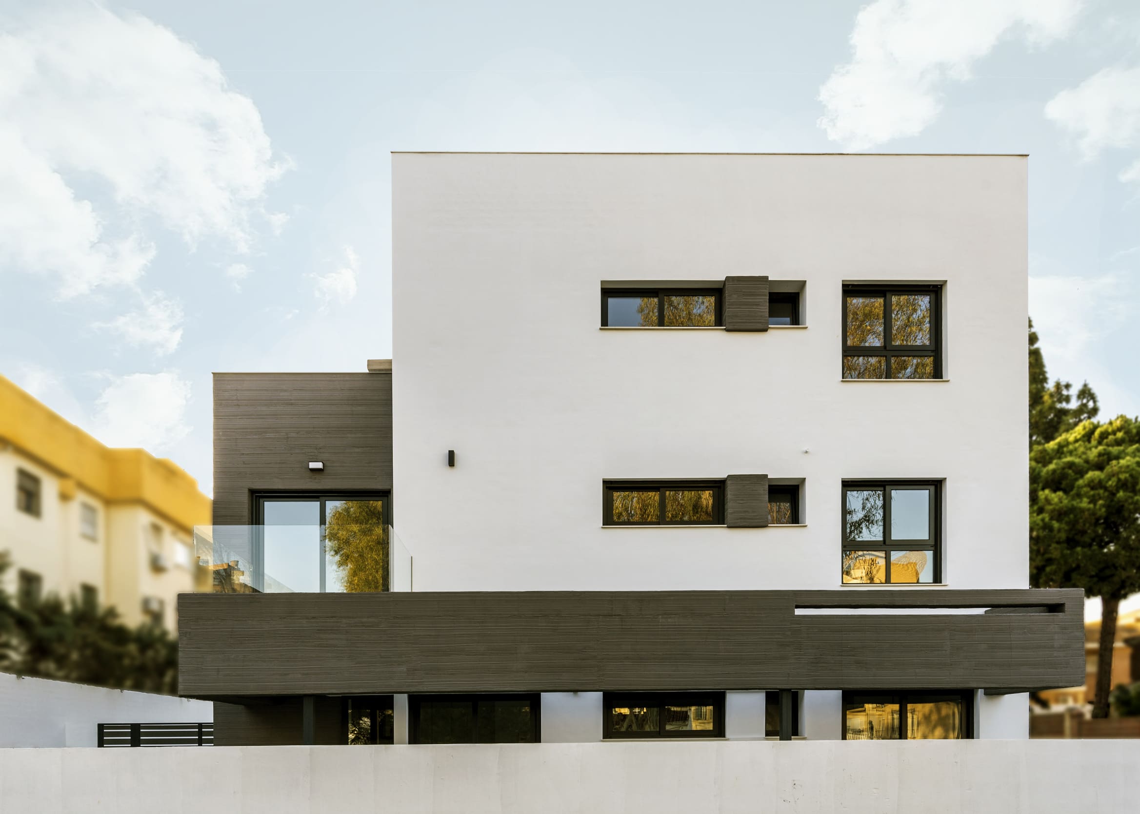 Elevación frontal de la Casa Ocaña mostrando huecos, voladizos y contraste de materiales