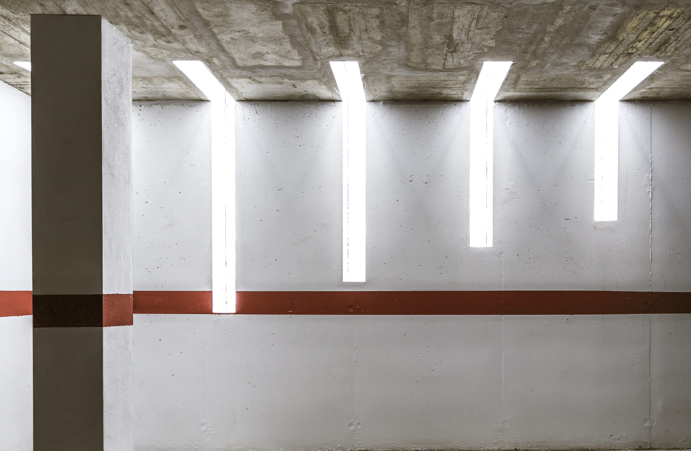 Interior de garaje de la Casa Ocaña con techo de hormigón y lucernarios lineales