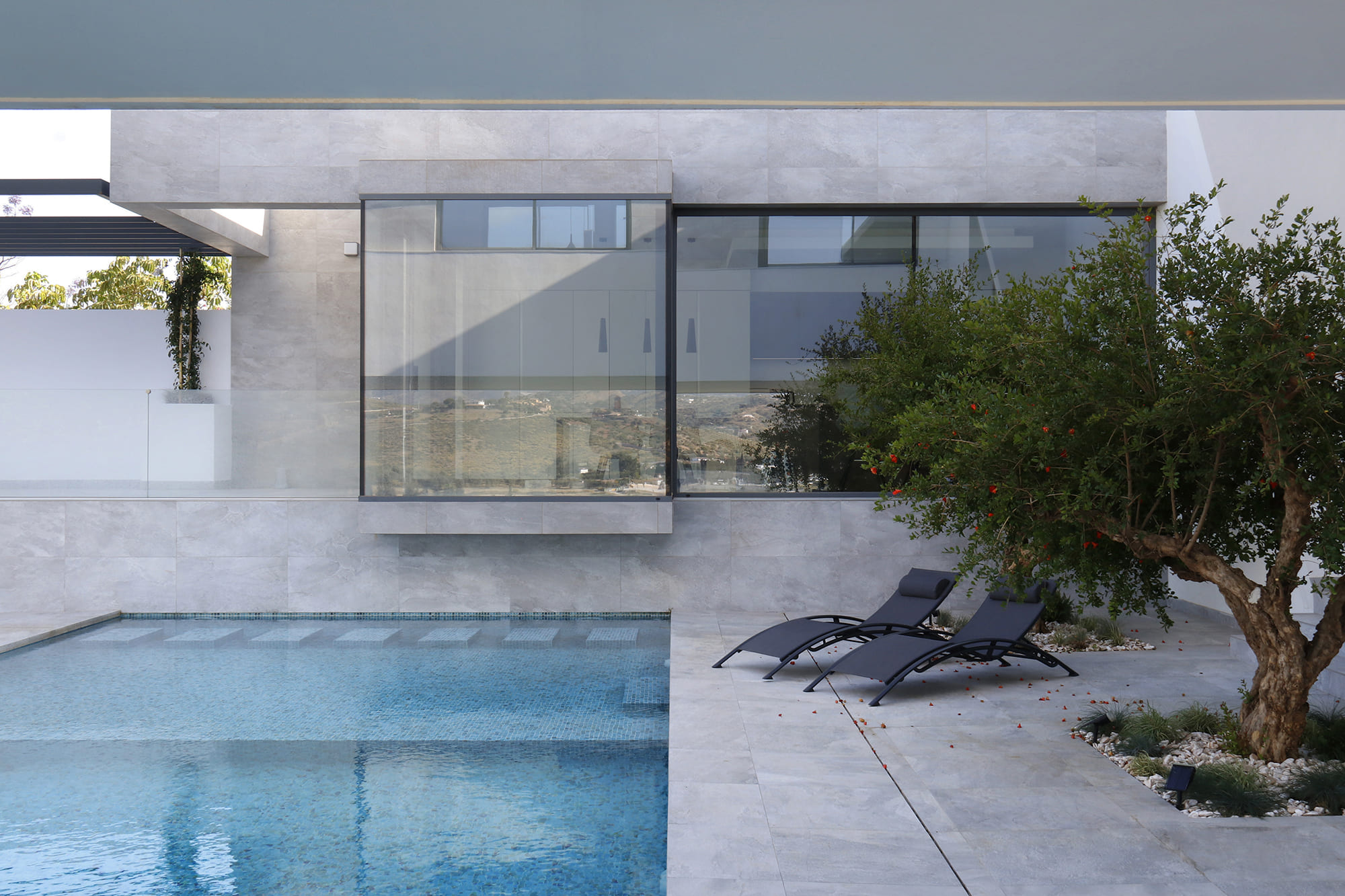 Figura en silueta junto a la piscina infinita bajo el voladizo, contemplando el valle malagueño