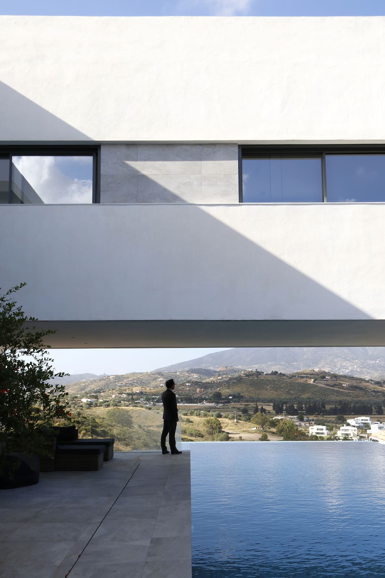 Fachada minimalista con ventana horizontal y sombra triangular sobre el muro blanco