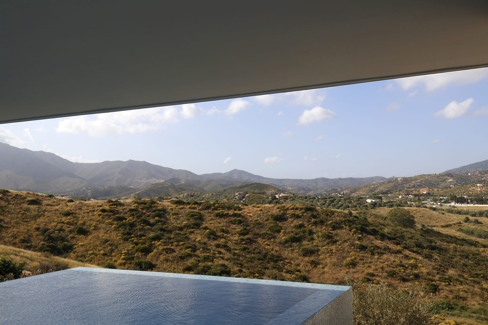 Segundo plano de la piscina infinita reflejando el voladizo y la ladera mediterránea