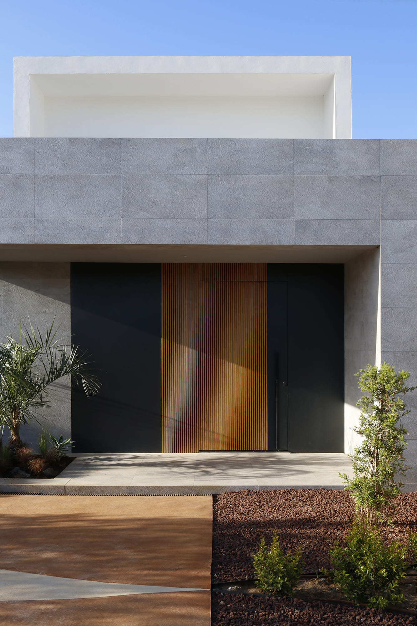 Detalle en primer plano de la puerta de acceso con listones de madera y panel negro de contraste