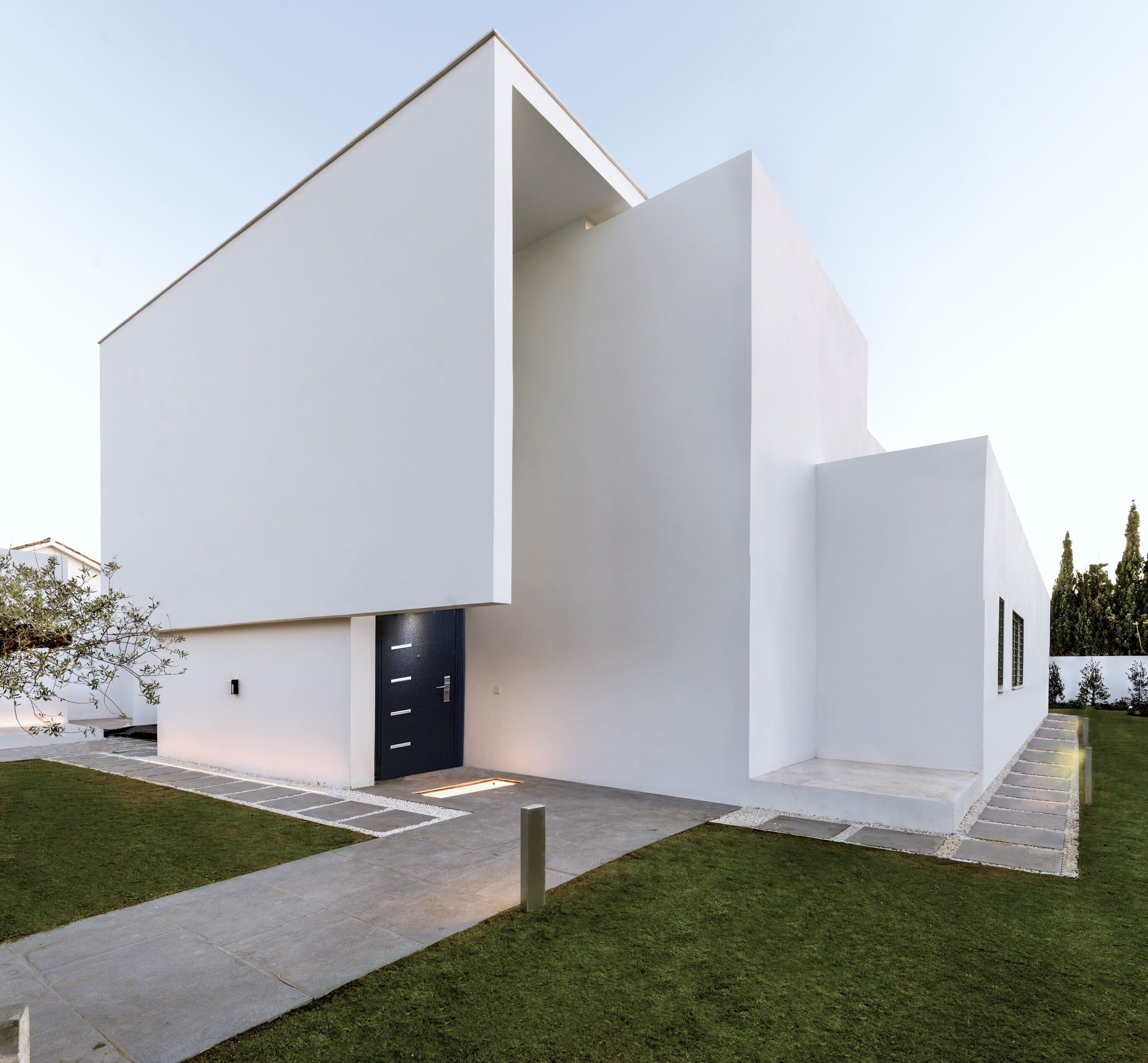 Vista lateral de la vivienda donde se aprecia la entrada secundaria, con imponentes paredes rectas balncas