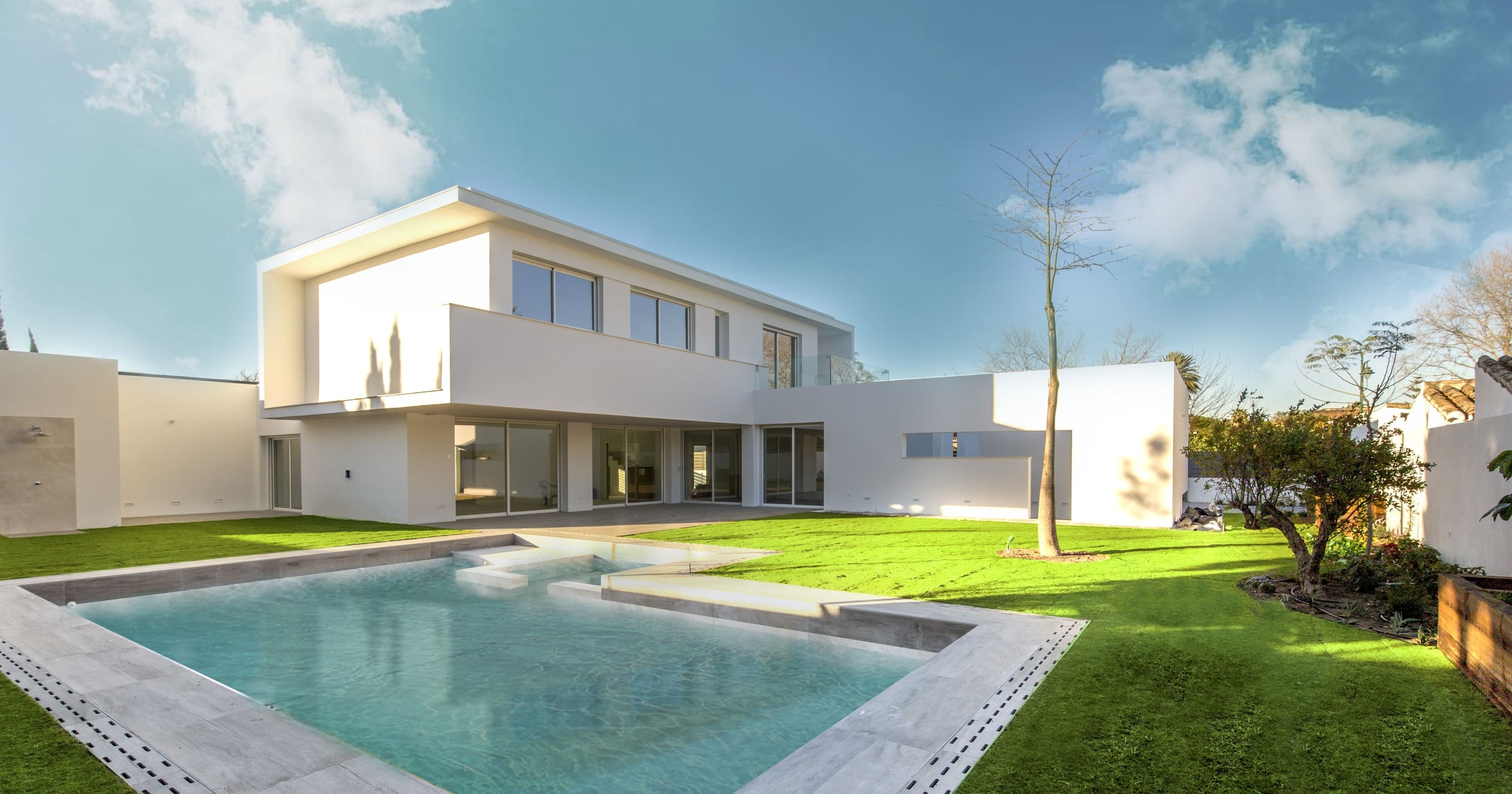 Piscina desbordante con vista trasera de la vivienda con su jardin