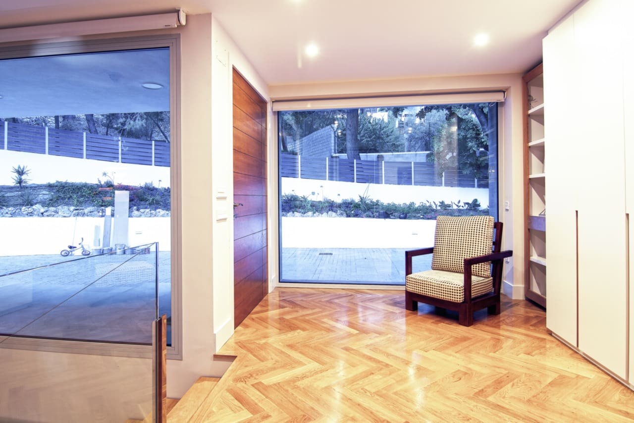 Interior de la Vivienda P∩C: salón con suelos de madera, grandes ventanales y salida directa a la terraza